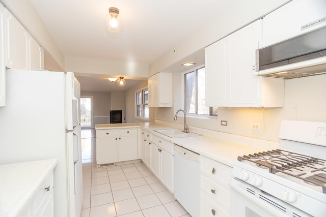 kitchen with sink, white cabinets, white appliances, light tile patterned floors, and kitchen peninsula