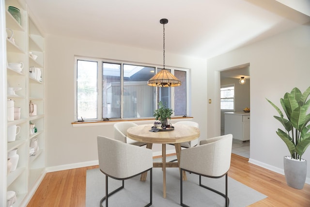 dining space featuring built in shelves, an inviting chandelier, and light hardwood / wood-style floors