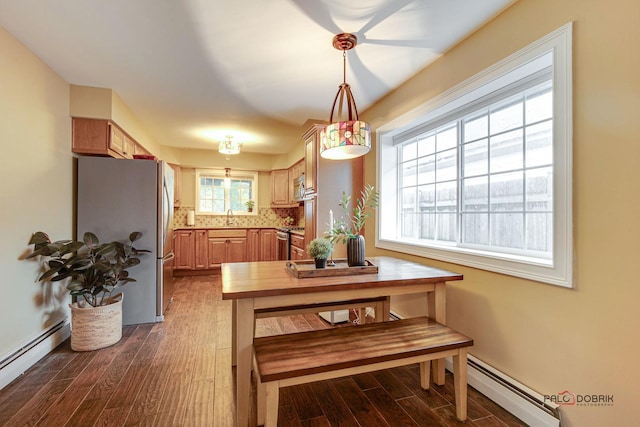 dining space featuring sink, a baseboard heating unit, and hardwood / wood-style floors