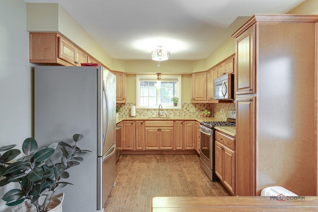 kitchen featuring sink, tasteful backsplash, light hardwood / wood-style floors, light brown cabinetry, and appliances with stainless steel finishes