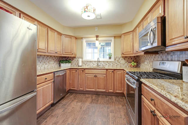 kitchen featuring stainless steel appliances, sink, light stone counters, backsplash, and dark hardwood / wood-style floors