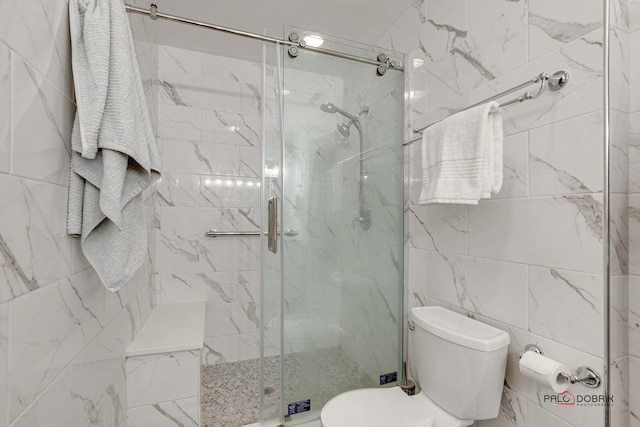 bathroom with tile walls, a shower with shower door, and toilet