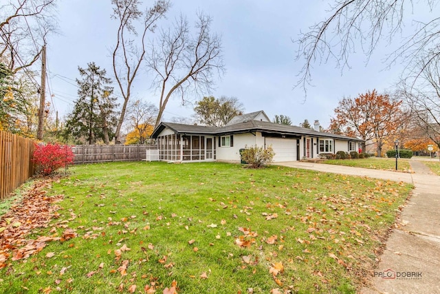 view of front of property featuring a front yard, a garage, and a sunroom