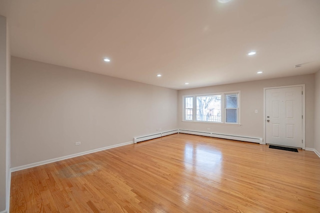 spare room featuring a baseboard radiator and light hardwood / wood-style flooring