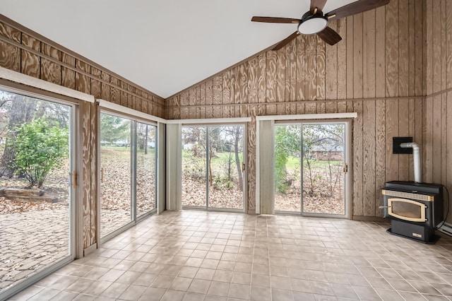 unfurnished sunroom with lofted ceiling, a wealth of natural light, ceiling fan, and a wood stove