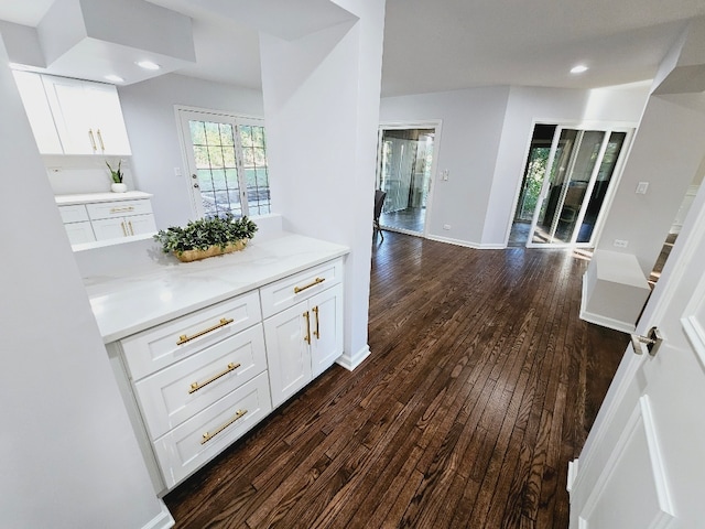 kitchen featuring dark hardwood / wood-style flooring, white cabinetry, and light stone counters