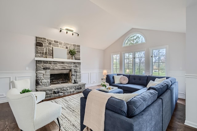 living room featuring lofted ceiling, dark wood-type flooring, and a stone fireplace