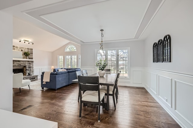 dining area featuring lofted ceiling, a fireplace, and dark hardwood / wood-style flooring