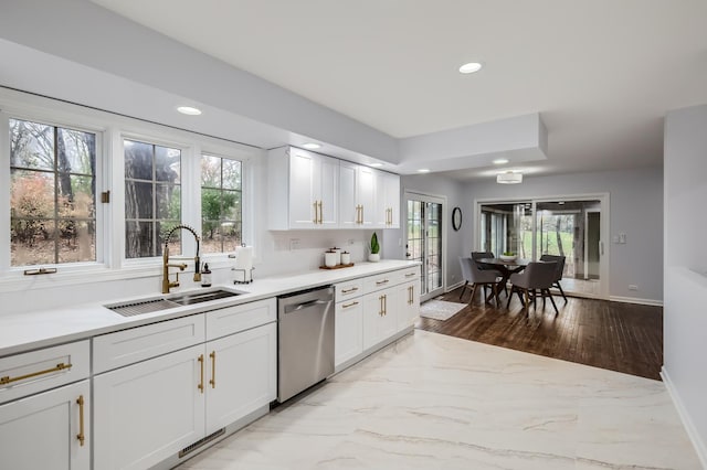 kitchen with stainless steel dishwasher, white cabinetry, and sink