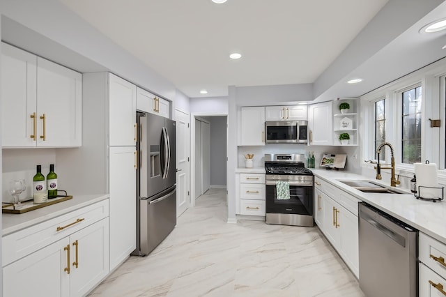 kitchen with appliances with stainless steel finishes, white cabinetry, and sink