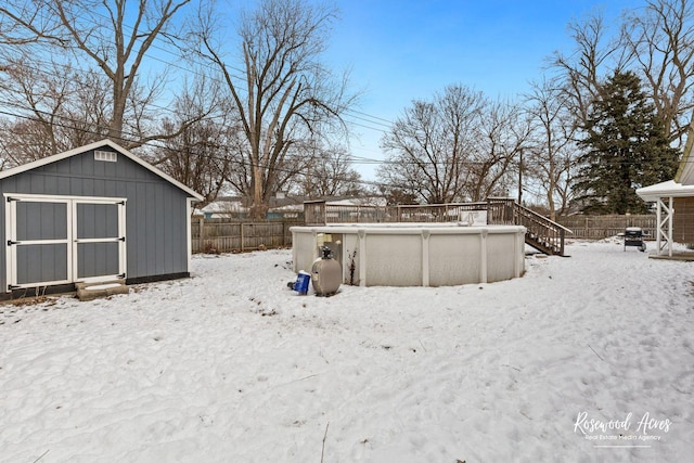 snowy yard featuring a fenced in pool and a storage shed