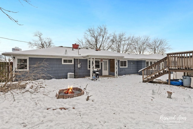 snow covered back of property featuring an outdoor fire pit and a wooden deck