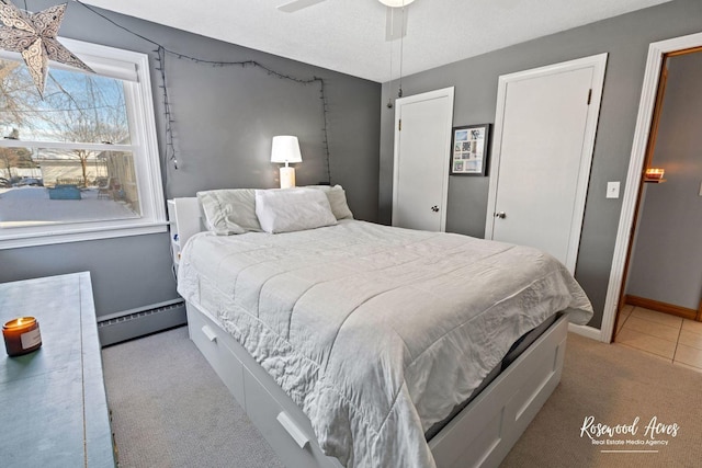 carpeted bedroom with ceiling fan, baseboard heating, and a textured ceiling