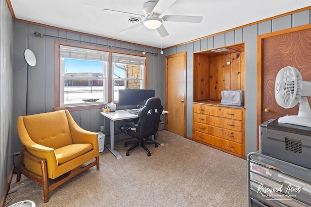 carpeted office featuring ceiling fan, crown molding, and wood walls