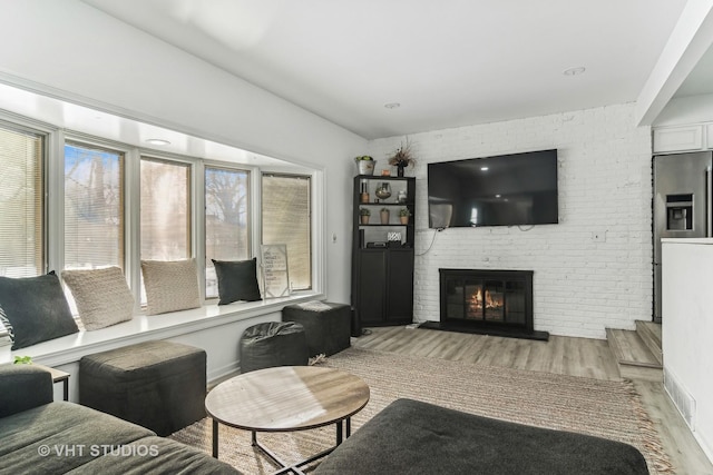 living room with a fireplace and light wood-type flooring