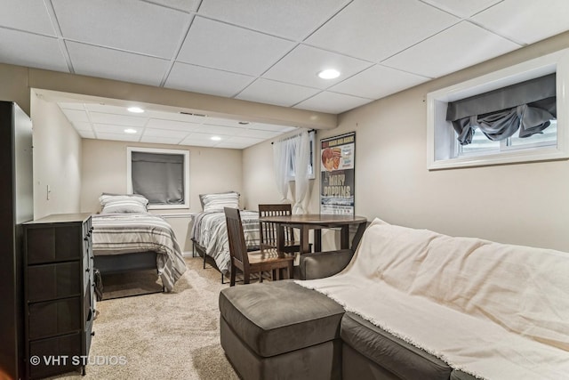 carpeted bedroom featuring a drop ceiling