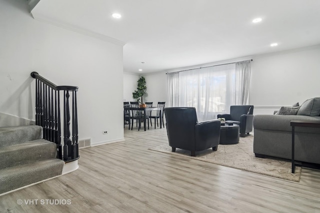 living room with ornamental molding and light hardwood / wood-style flooring