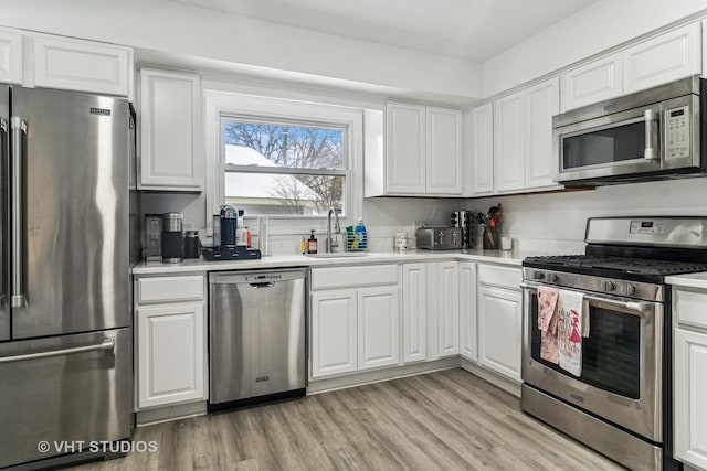 kitchen featuring white cabinetry, stainless steel appliances, light hardwood / wood-style floors, and sink