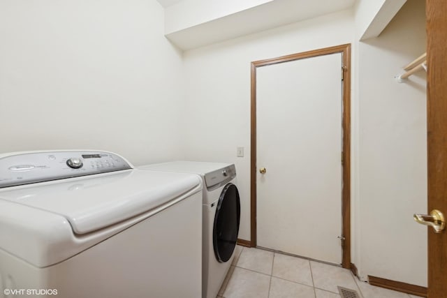 laundry room featuring washing machine and dryer and light tile patterned flooring