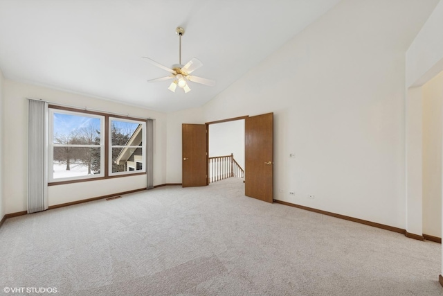 empty room with ceiling fan, light colored carpet, and high vaulted ceiling