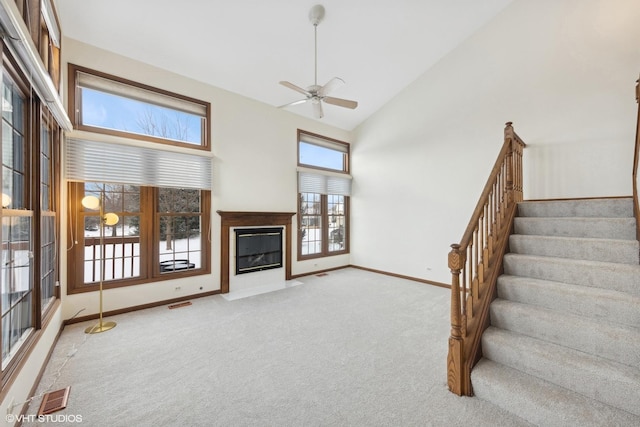 unfurnished living room with high vaulted ceiling, light carpet, and ceiling fan