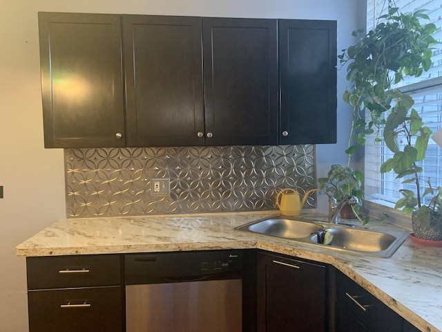 kitchen featuring light stone counters, stainless steel dishwasher, backsplash, and sink