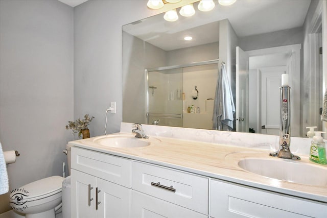 bathroom with vanity, a shower with shower door, and toilet