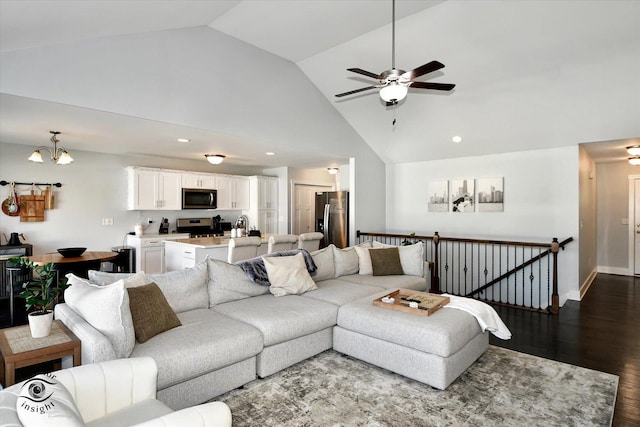 living room with ceiling fan with notable chandelier, wood-type flooring, and high vaulted ceiling