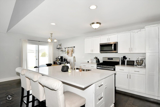 kitchen featuring sink, stainless steel appliances, white cabinetry, and a center island with sink