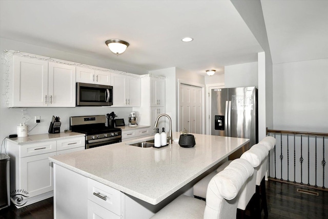 kitchen with appliances with stainless steel finishes, white cabinets, a kitchen island with sink, and sink