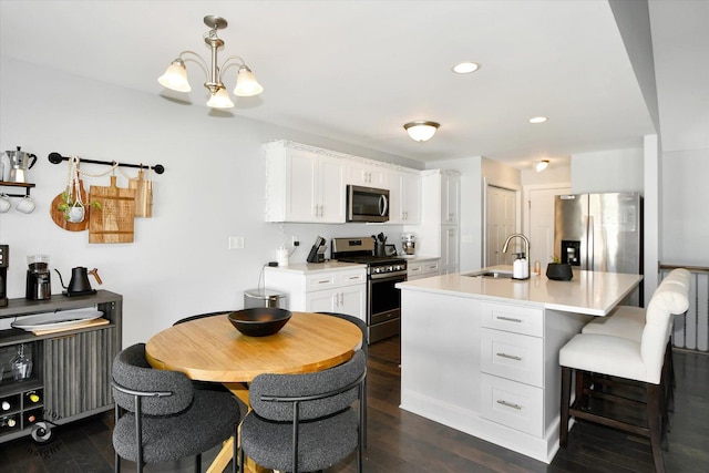 kitchen with a center island with sink, dark hardwood / wood-style flooring, white cabinetry, appliances with stainless steel finishes, and sink