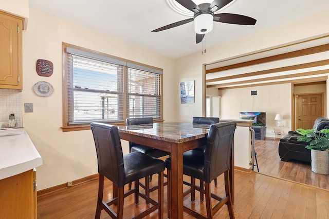 dining area featuring beam ceiling, light hardwood / wood-style floors, and ceiling fan