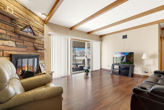 living room featuring dark wood-type flooring, a fireplace, and beam ceiling