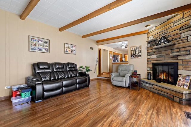 living room with hardwood / wood-style flooring, ceiling fan, a fireplace, and beamed ceiling