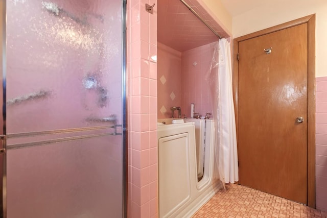 bathroom featuring a tile shower and washer / dryer