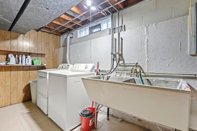 clothes washing area with wooden walls, sink, and independent washer and dryer