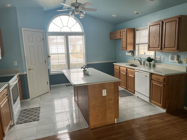 kitchen with light countertops, white appliances, a sink, and brown cabinets