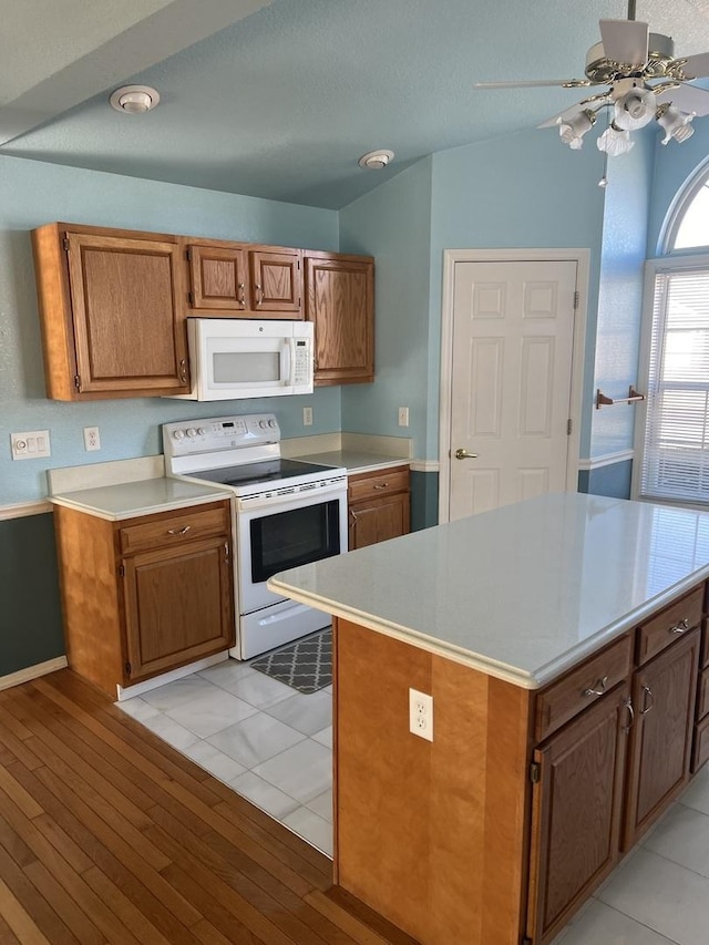 kitchen featuring brown cabinets, white appliances, and light countertops