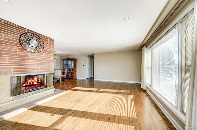 unfurnished living room with a multi sided fireplace, a chandelier, and hardwood / wood-style flooring