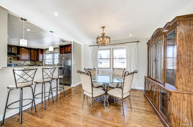 dining area featuring a healthy amount of sunlight, light wood-type flooring, sink, and a chandelier