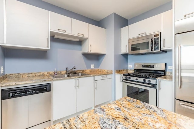 kitchen with sink, white cabinetry, light stone counters, and appliances with stainless steel finishes