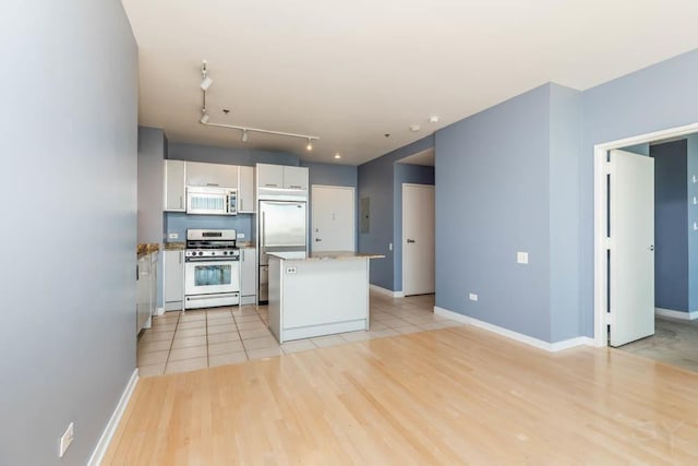 kitchen featuring stainless steel appliances, track lighting, white cabinetry, and light hardwood / wood-style floors