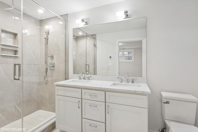 bathroom featuring vanity, a shower with shower door, and toilet