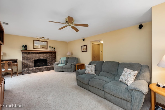 living room featuring a brick fireplace, ceiling fan, and carpet