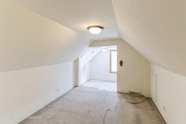 additional living space with lofted ceiling, visible vents, and carpet