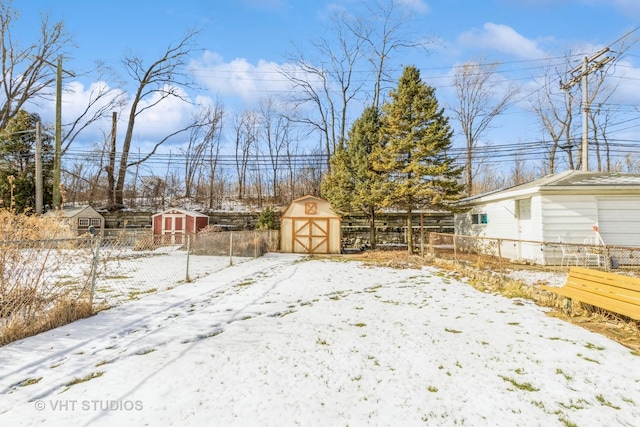 snowy yard featuring a storage unit