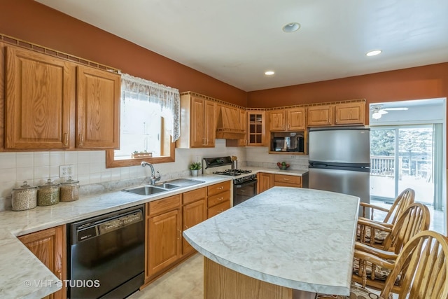 kitchen featuring brown cabinets, custom range hood, decorative backsplash, a sink, and black appliances