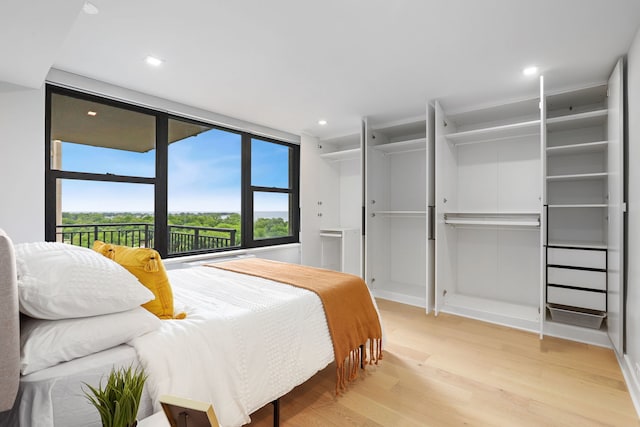 bedroom featuring a wall of windows and light hardwood / wood-style flooring