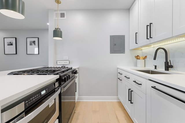 kitchen with gas stove, electric panel, pendant lighting, sink, and white cabinetry