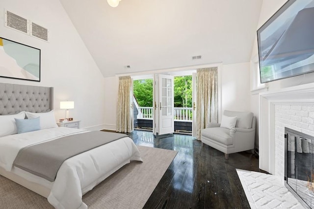 bedroom with dark hardwood / wood-style flooring, high vaulted ceiling, a brick fireplace, and access to outside